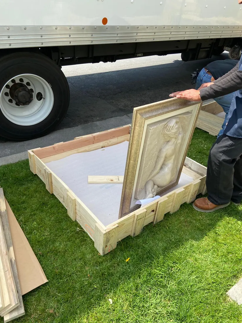Before: a wall art sculpture being set into an open wooden crate